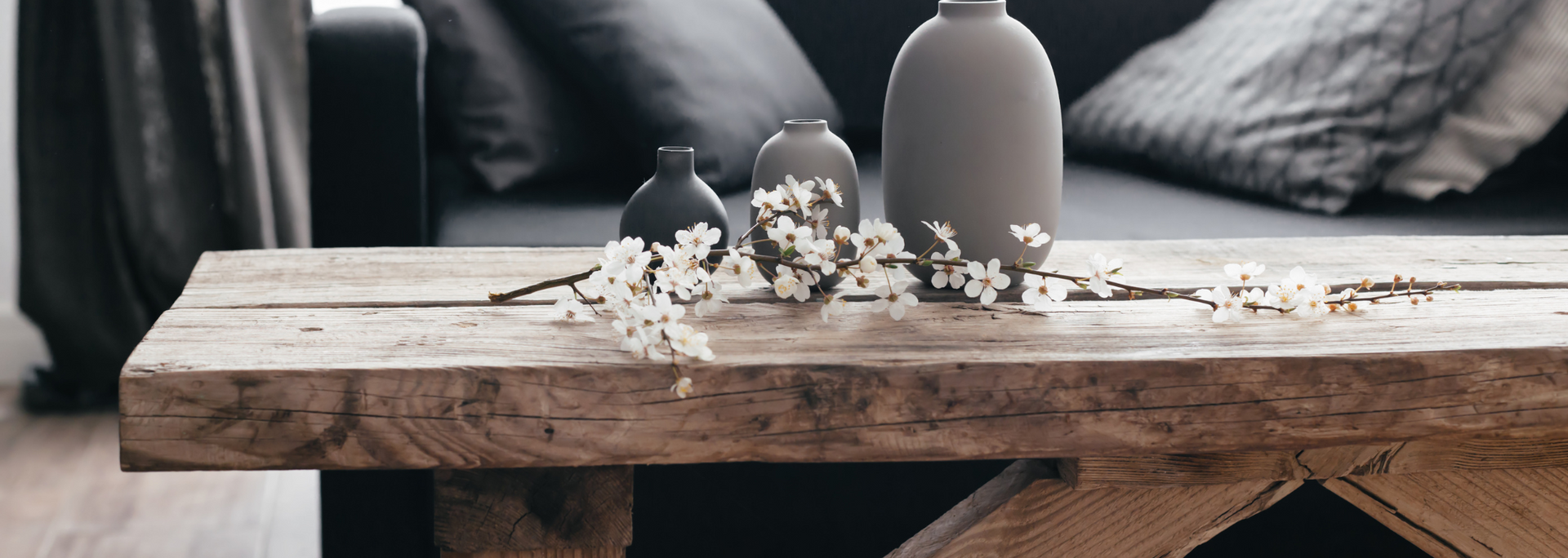 Rustic wooden coffee table with a vase and white flowers in a cozy gray living room
