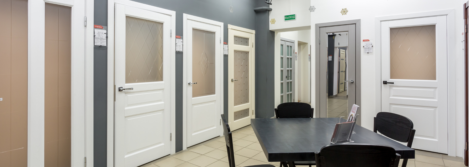 White interior with multiple doors, chairs, and mirrors in a bright hallway reception area