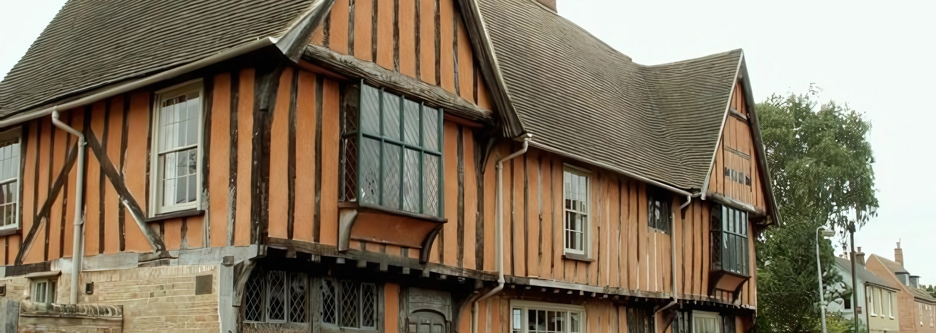 Old timber-framed building with orange walls and black-trimmed windows along a street