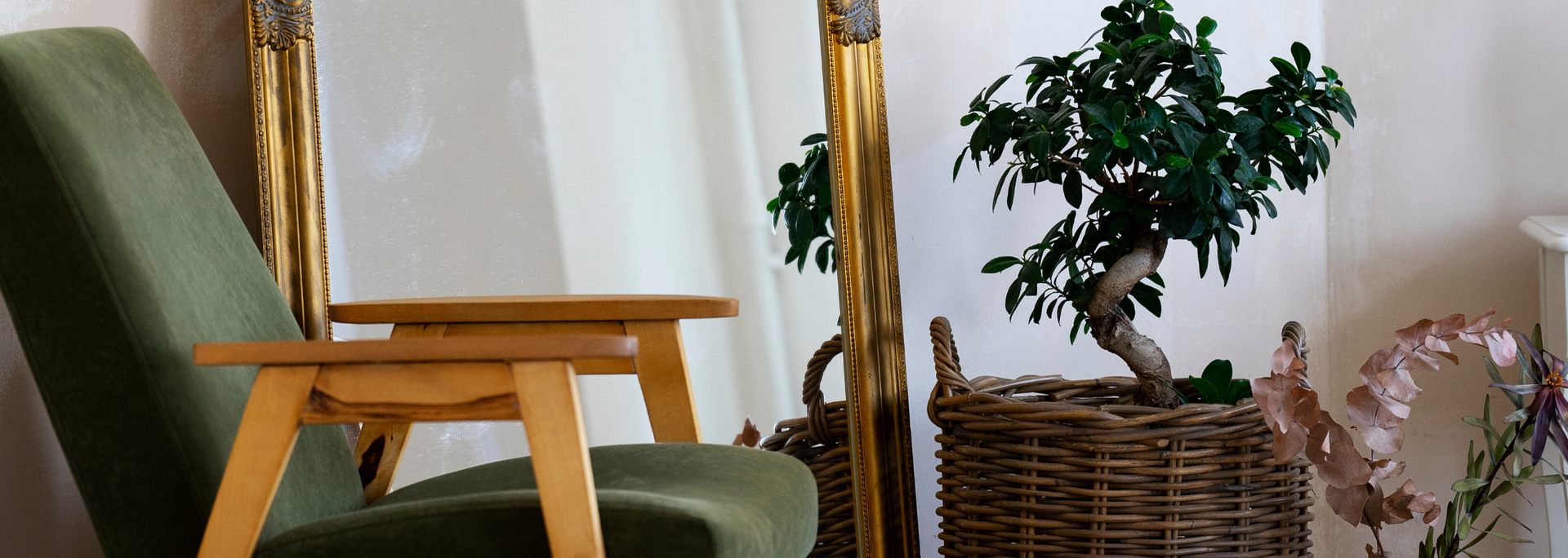 Green armchair beside a wicker basket and potted plant in a bright room