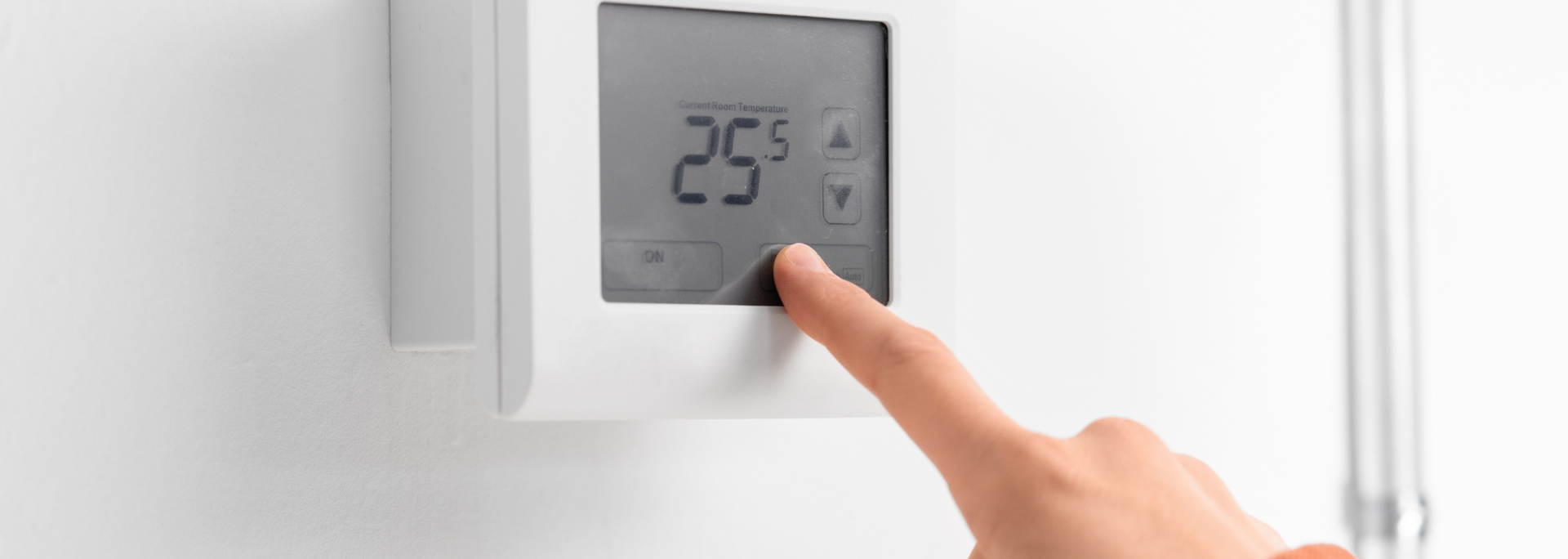 Finger touching a white thermostat display showing 25°
