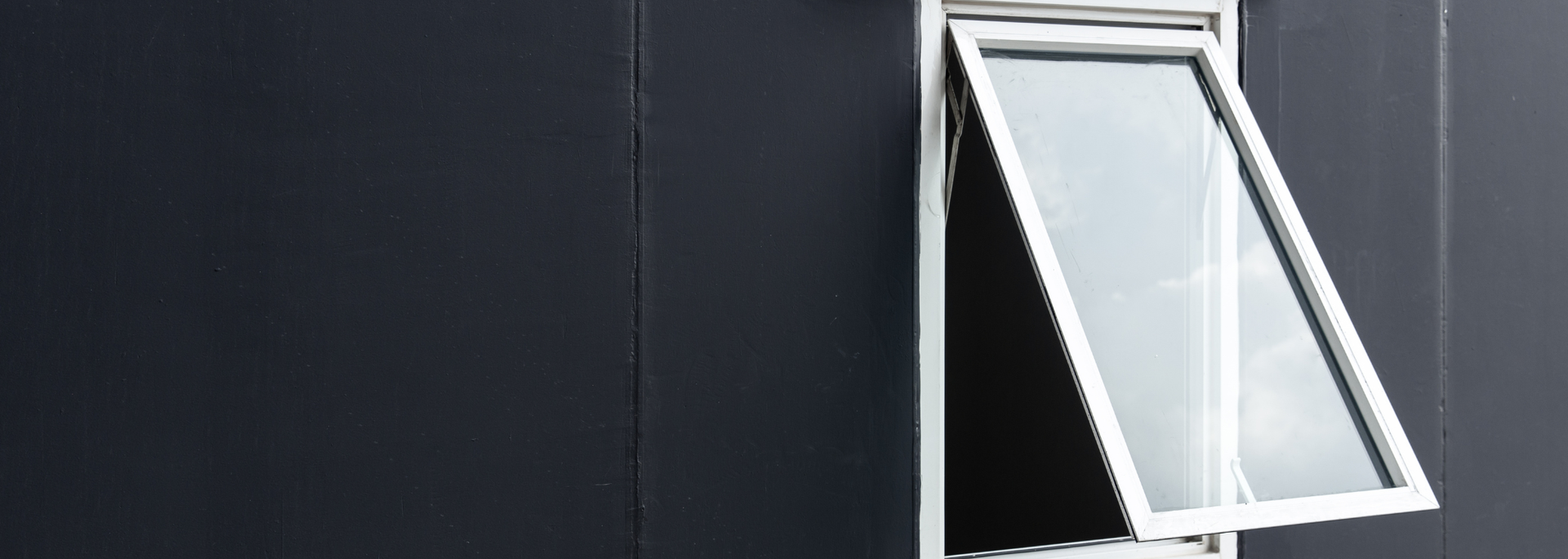White-framed window propped open on a dark exterior wall.