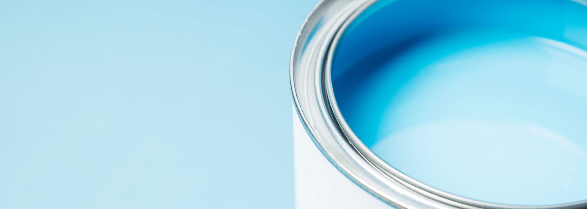 Close-up of a blue cosmetic cream jar with a silver rim on a light blue background