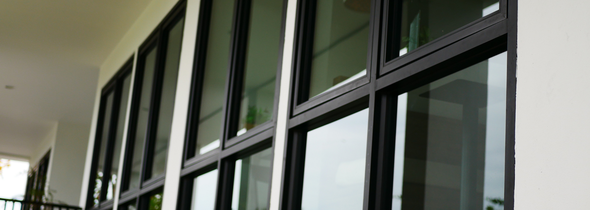 Glass windows and black frames along a modern building corridor with white walls
