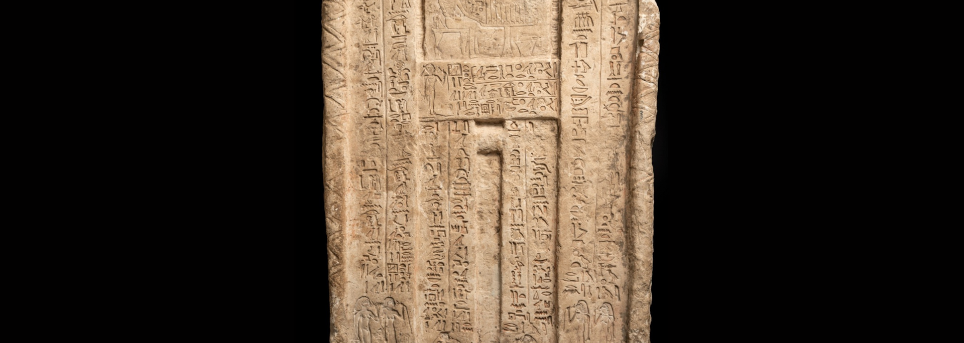 Close-up of an ornate carved wooden panel with a central recessed door and geometric floral patterns