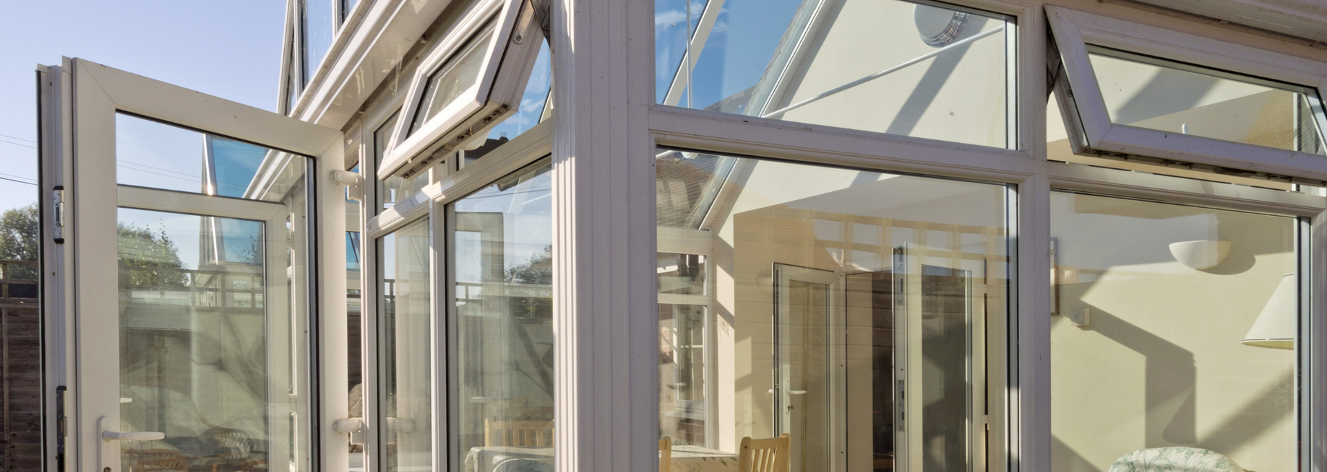 Glass-enclosed modern walkway with metal frames and sunlit interior reflections