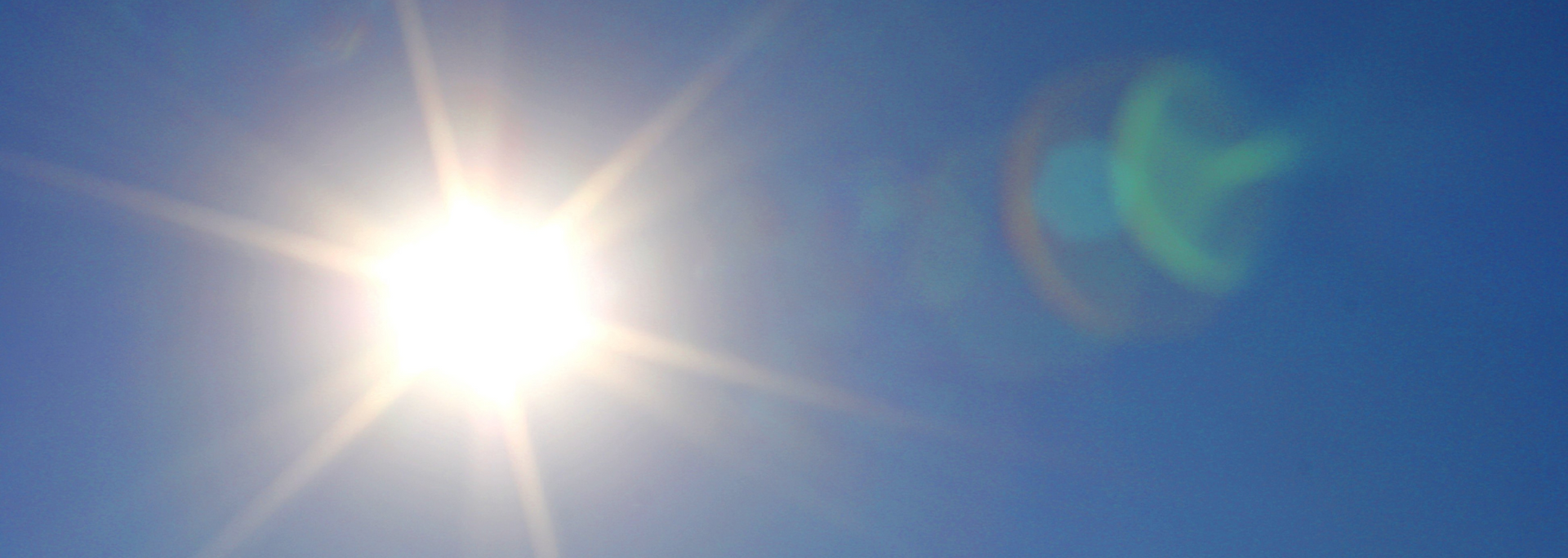 Bright sun in a clear blue sky with lens flare