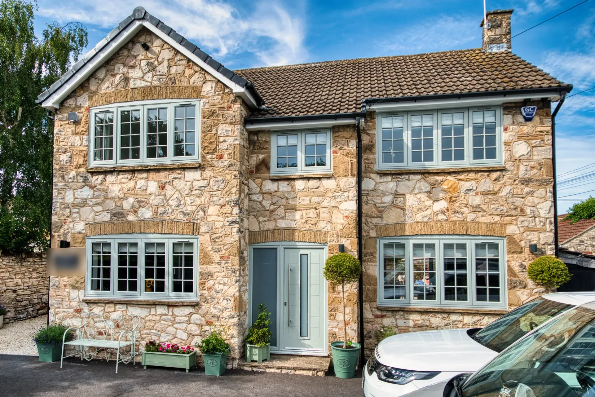 Brick house exterior with large windows and flowering greenery along the wall