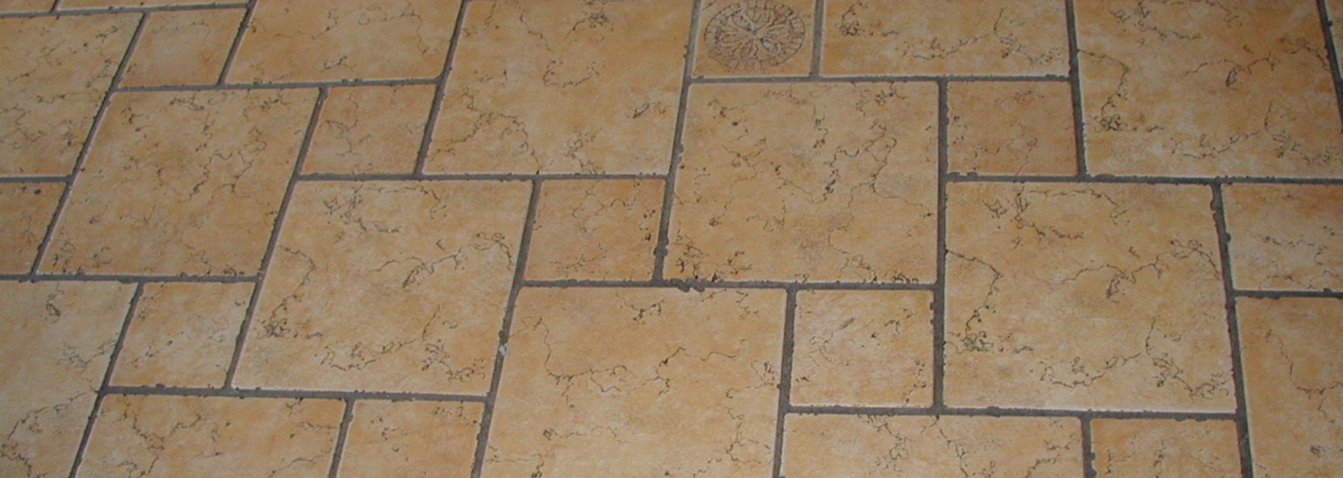 Close-up of tan stone pavers with dark grout lines in a patio or walkway pattern