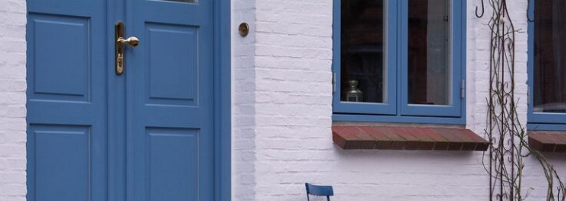 Blue front door and window on a white brick house facade