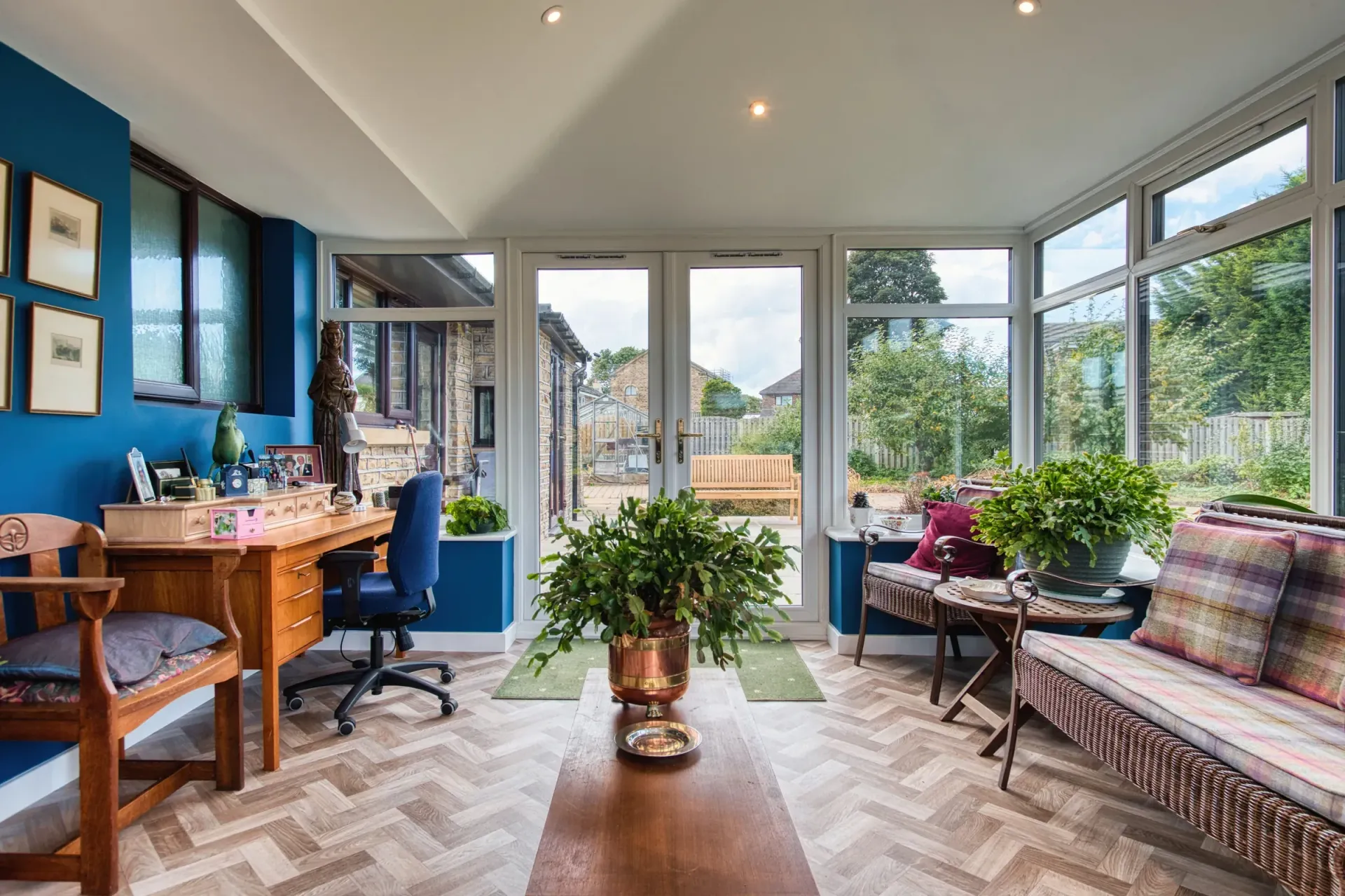 White conservatory extension attached to a brick house with a glass roof and windows