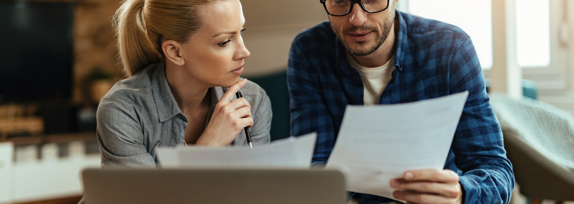 Two coworkers reviewing a document together at a desk with a laptop in a modern office