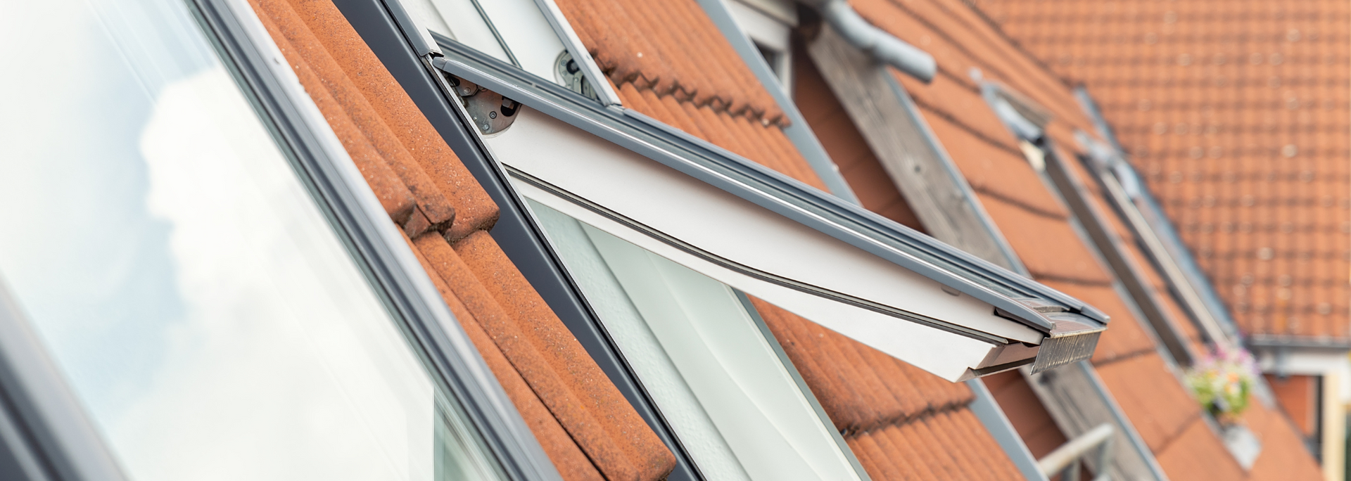 Close-up of red roof tiles with a silver metal ladder or roof walkway attached to a house.