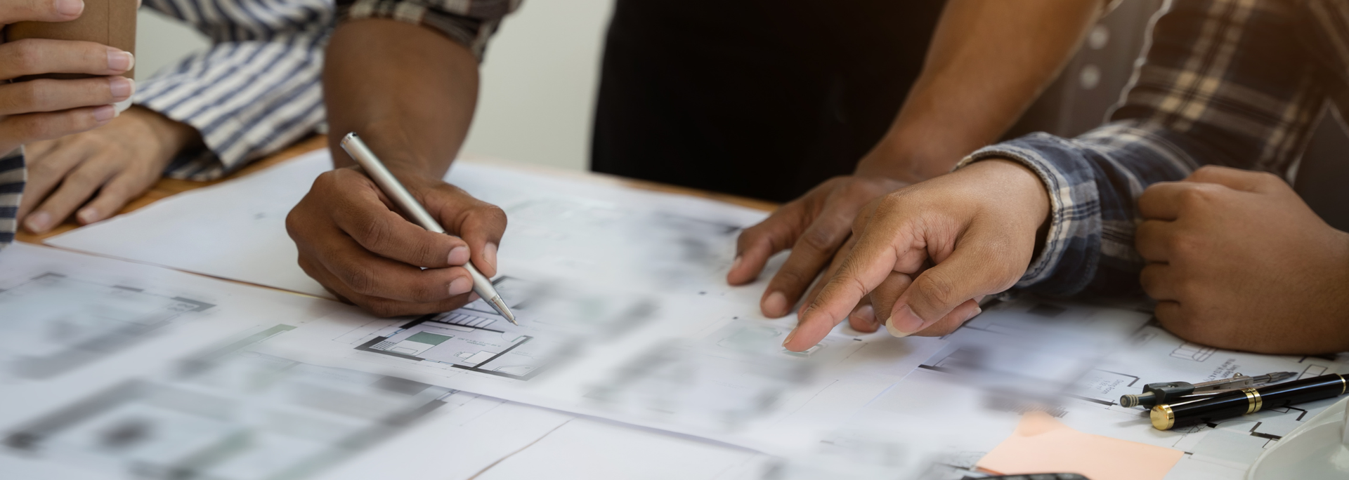 People collaborating at a table, pointing and writing on printed documents during a planning meeting