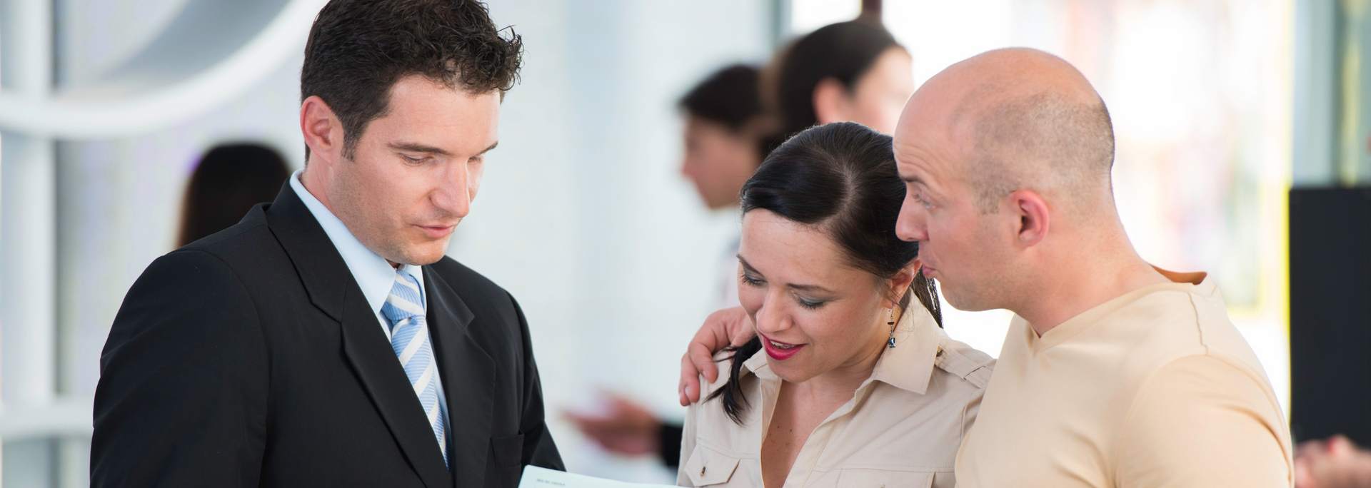 Three office coworkers looking at a phone and discussing something