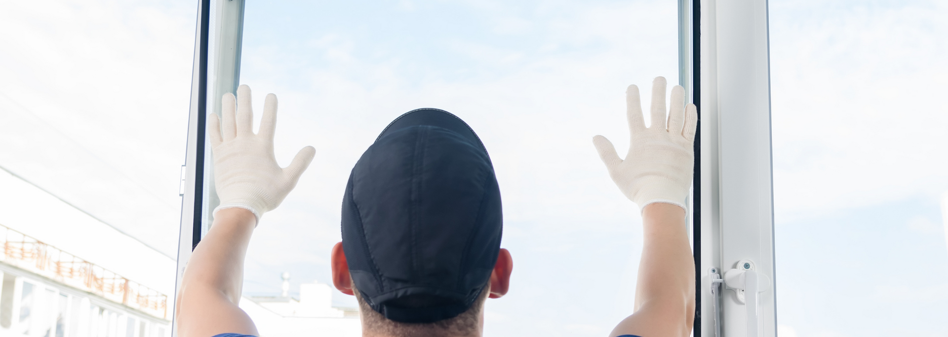 Person wearing gloves and a cap presses both hands against a bright window.