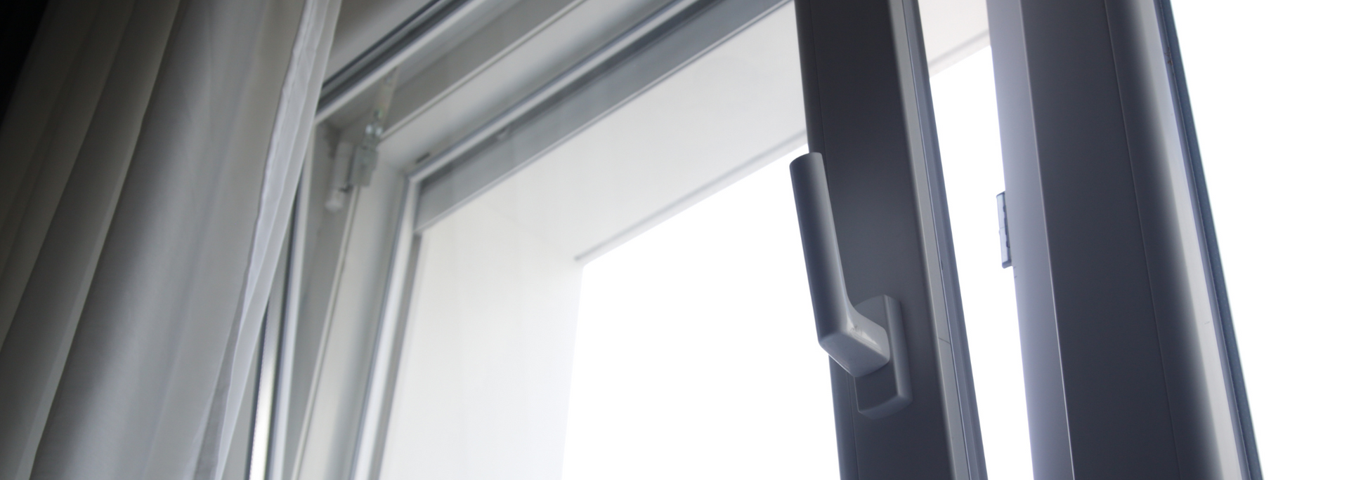 Partially open white window with gray curtains and a black frame