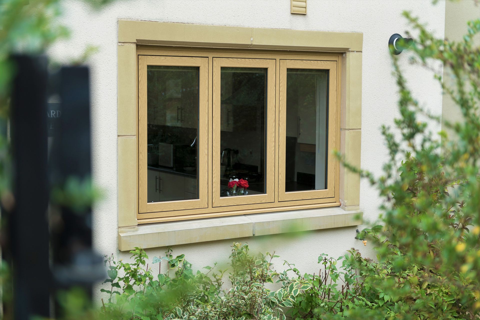 White-framed bay window on a brick house above green shrubbery