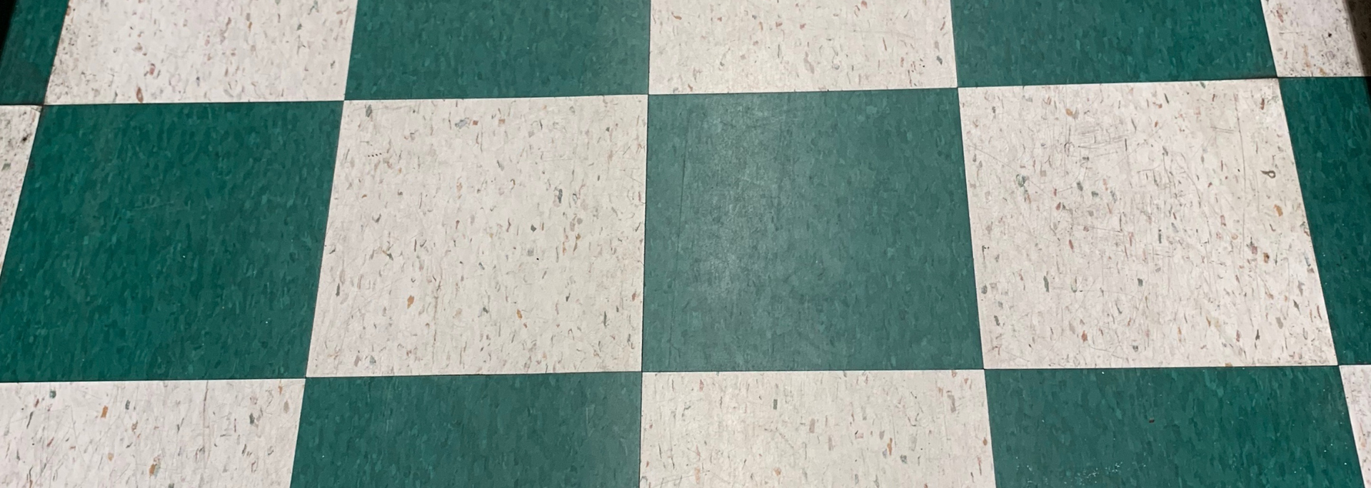 Green and white checkered tiled floor with speckled texture