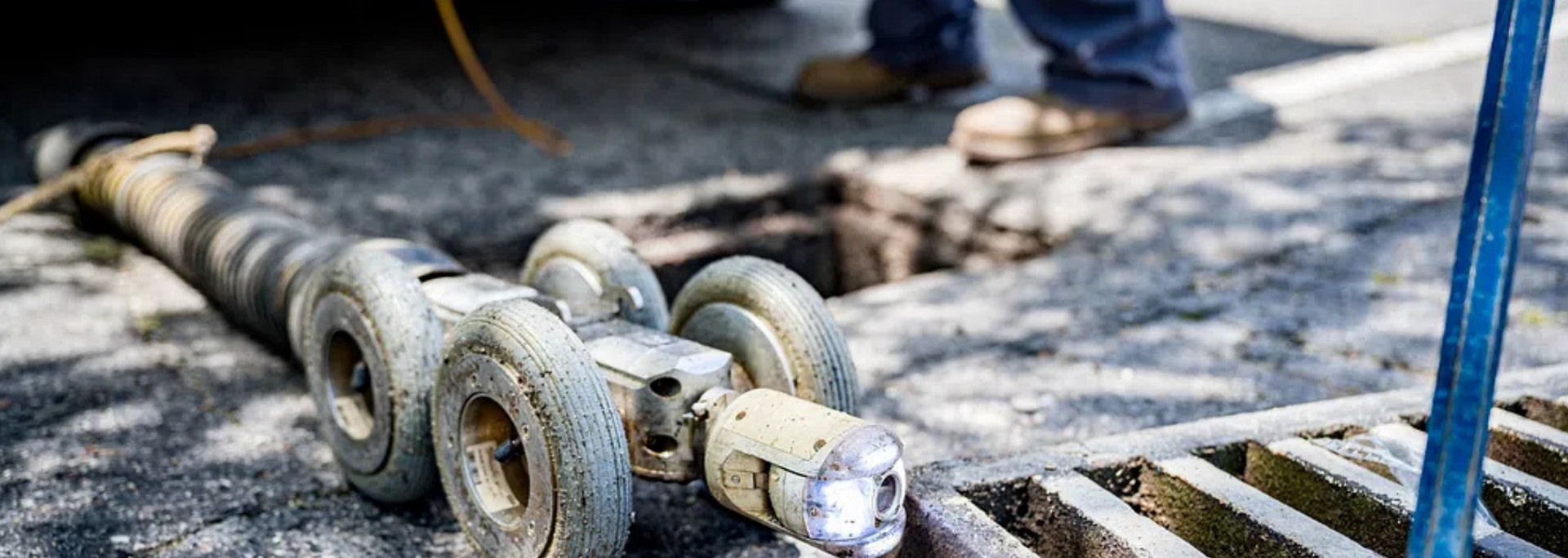 Rusty industrial chain laid on a wet concrete floor beside a blue metal pole.