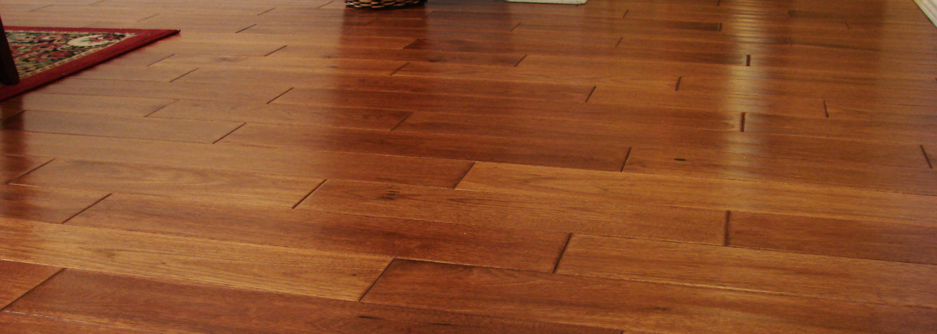 Wooden floorboards with a small patterned rug corner in the upper left.