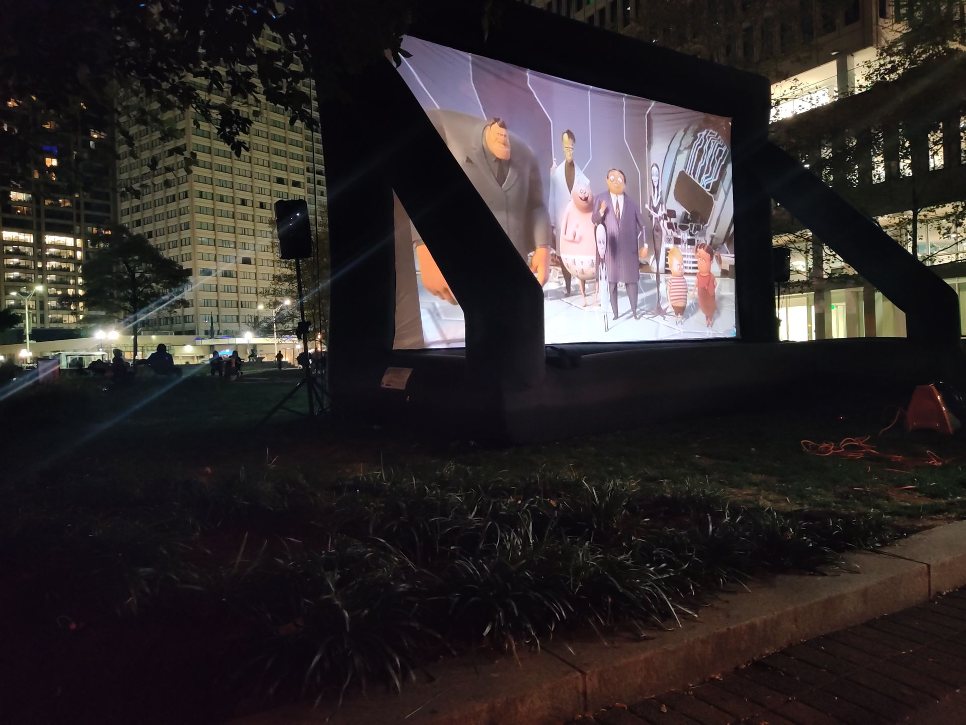 A large inflatable screen is displaying a movie at night