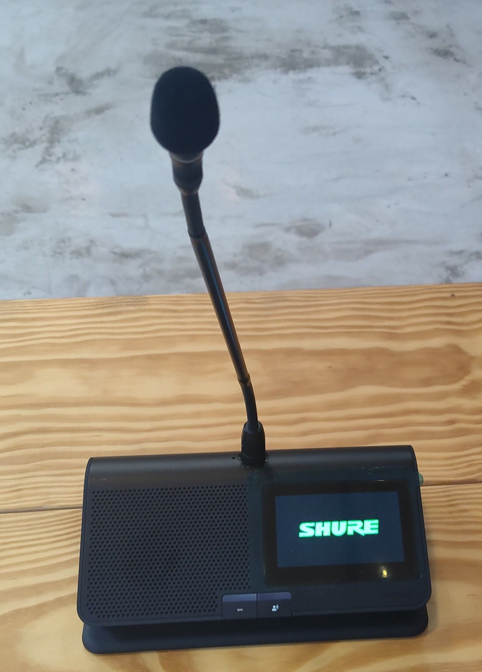 A shure microphone sits on a wooden table