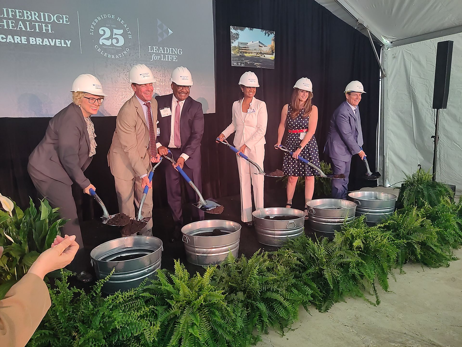 A group of people wearing hard hats are digging in buckets.