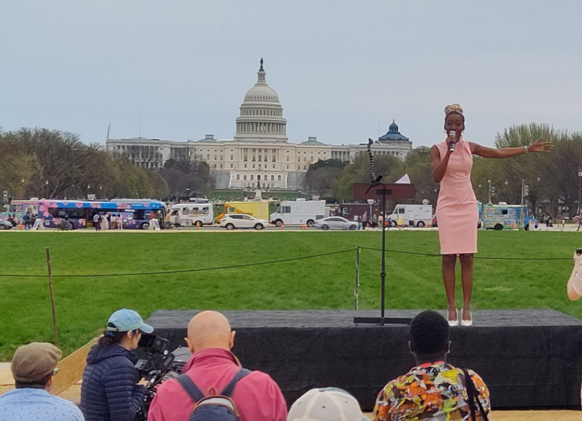 A woman in a pink dress is singing into a microphone in front of a crowd