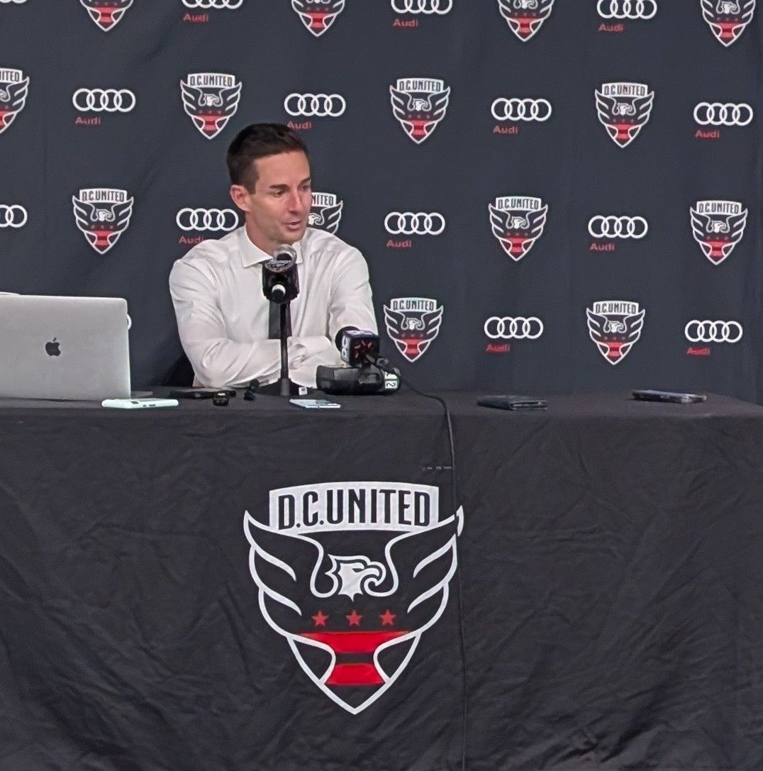 A man sitting at a table with a d.c. united logo on it
