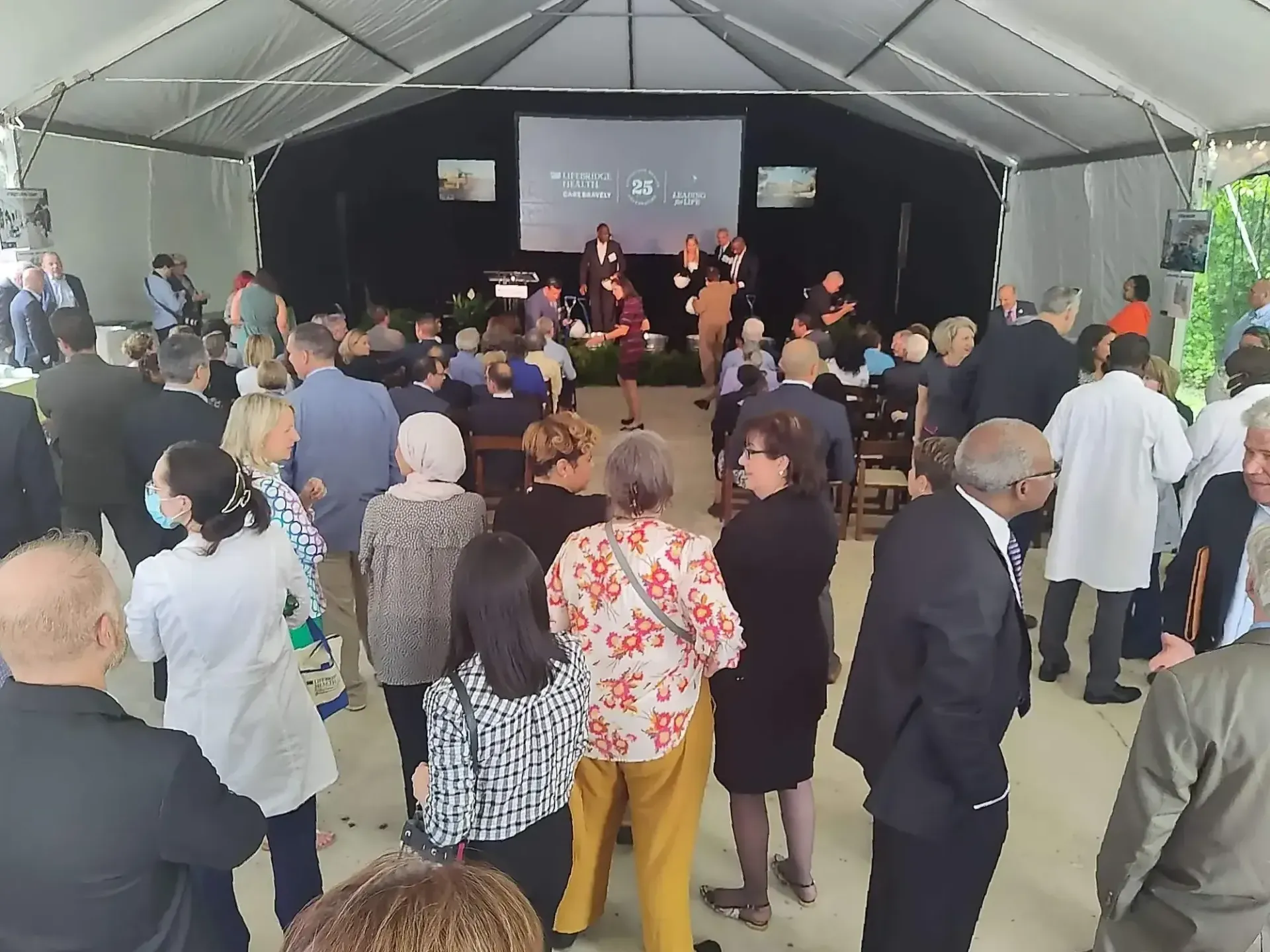A large group of people are gathered under a tent