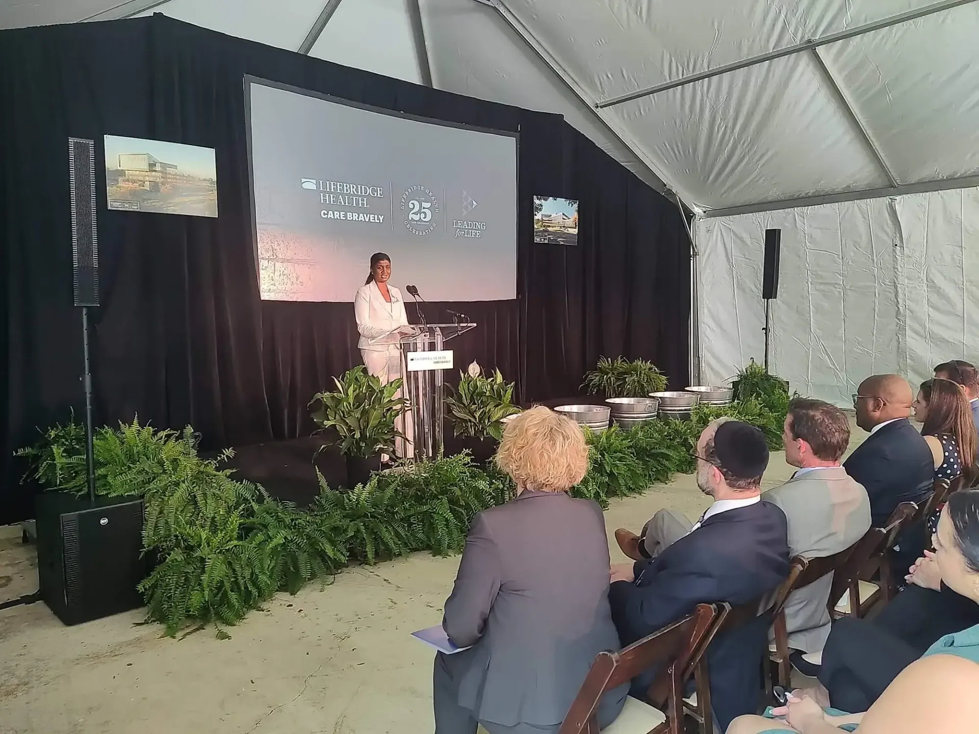 A woman stands at a podium giving a presentation to a group of people