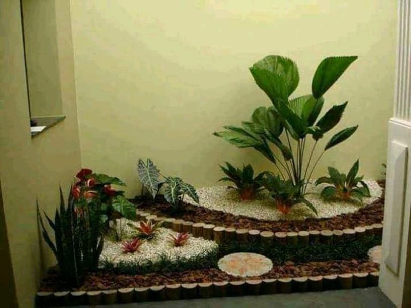 Un giardino pensile a più livelli per interni, con piante in vaso, pietre decorative bianche e bordi in tronchi di legno, su uno sfondo color crema.