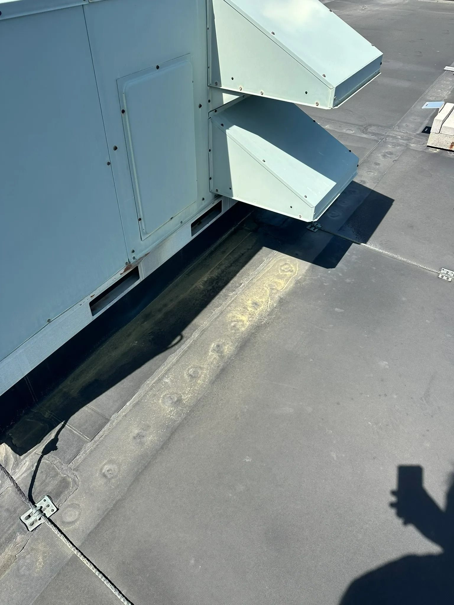 Industrial rooftop vent ducts on a flat roof with a person’s shadow nearby
