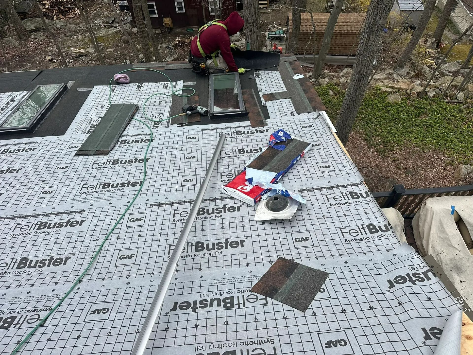 Workers installing roofing underlayment on a flat roof with tools and materials scattered nearby