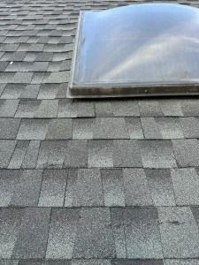 Close-up of a shingled roof with a clear skylight dome.