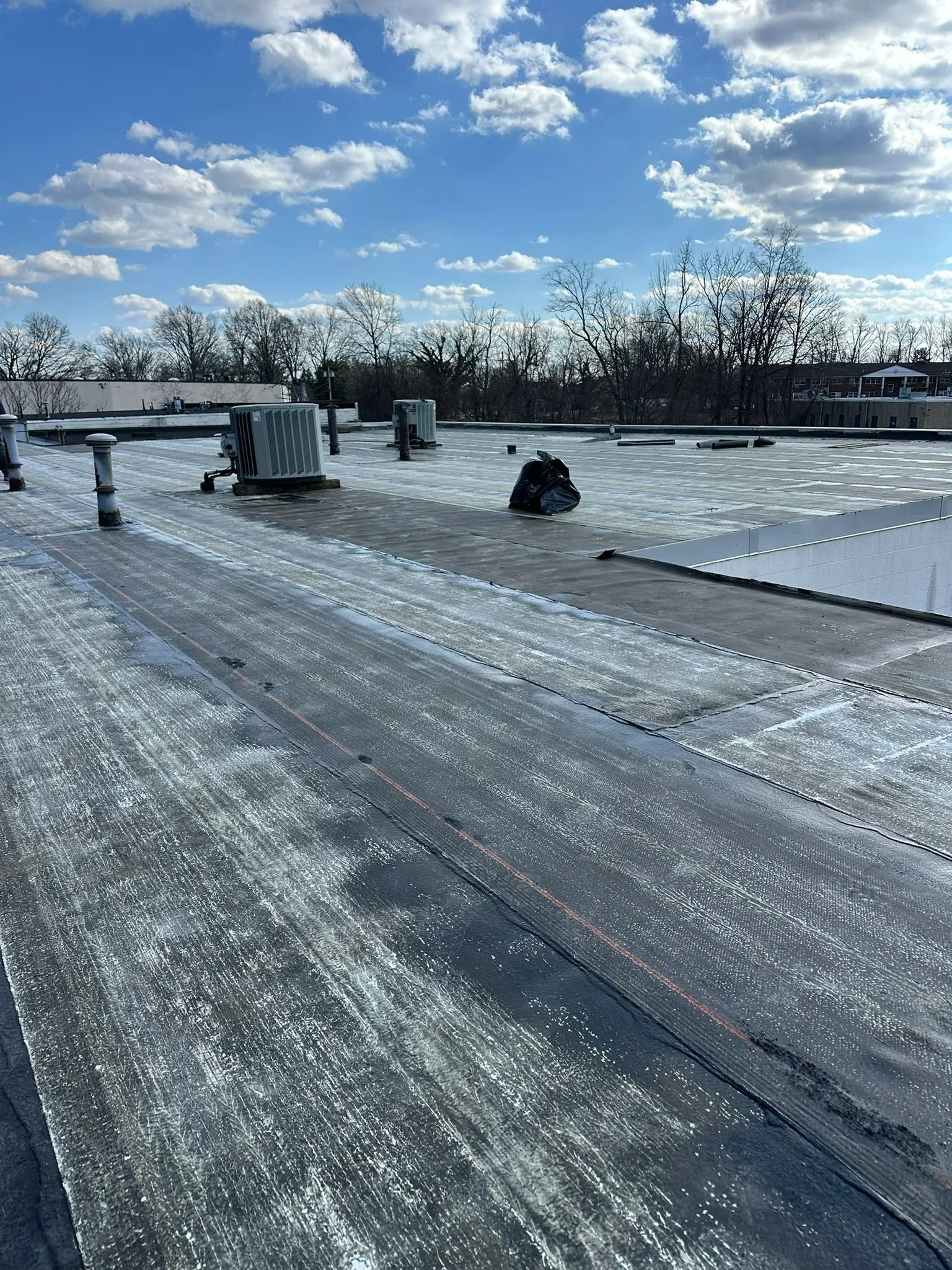 Snowy rooftop with a person sitting near the edge under a blue sky with clouds