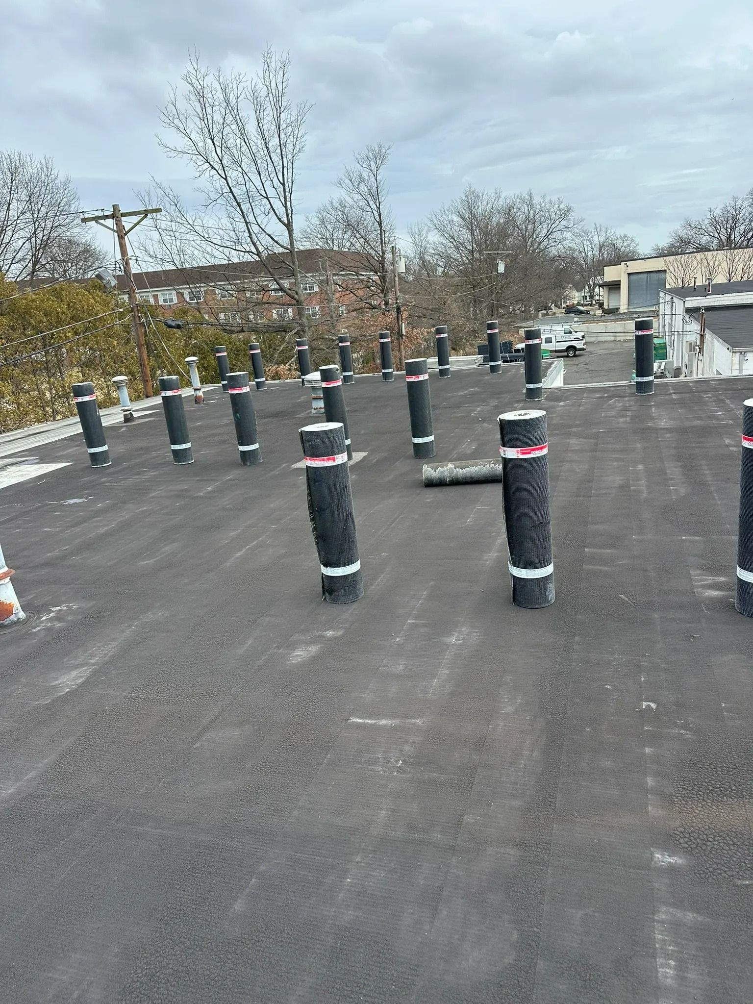 Rooftop with black ventilation posts capped in white and red, under a cloudy sky.