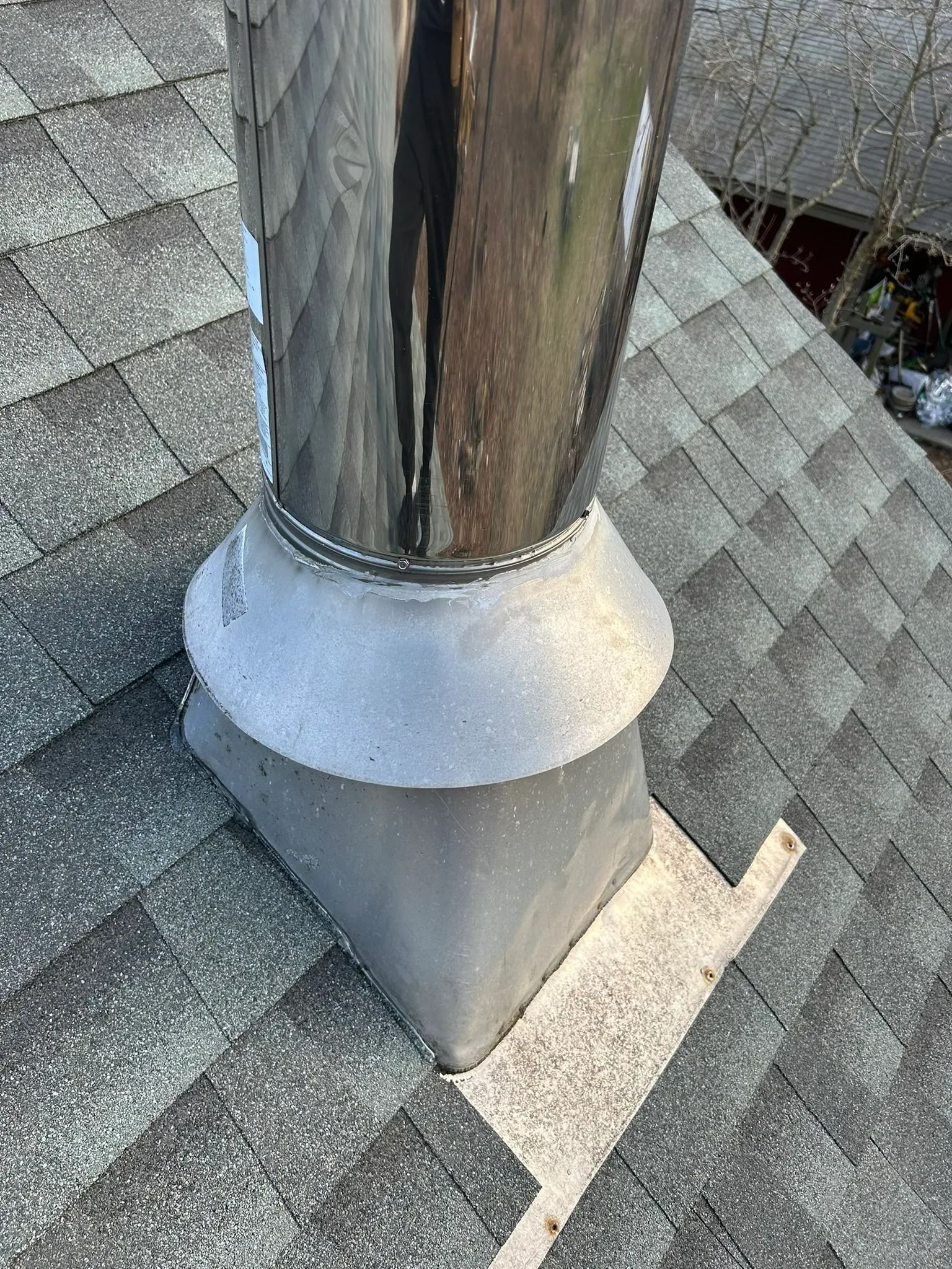 Rooftop chimney pipe with gray flashing on asphalt shingles