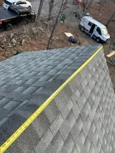 Rooftop edge with yellow safety line, viewed above parked vehicles and a wooded area below