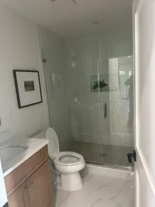 Modern bathroom with toilet, vanity, and glass-enclosed shower in neutral tones