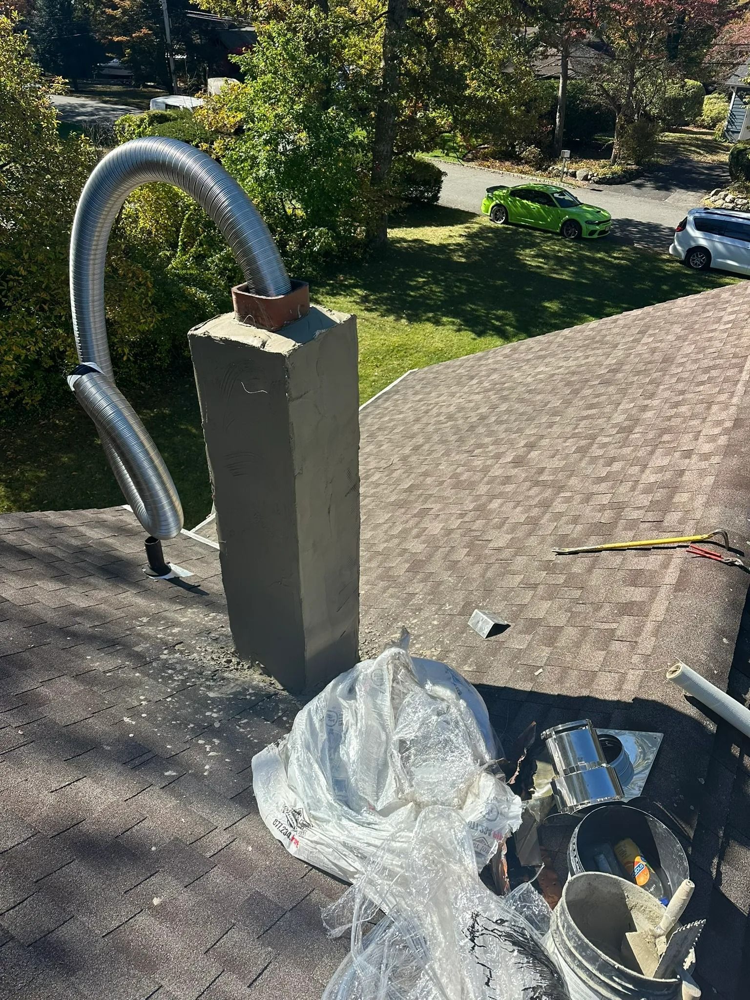 Rooftop with vent pipe, chimney, tools, and a plastic bag in sunlight