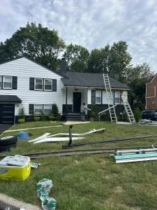 House with roof repair supplies and ladders scattered across the front lawn