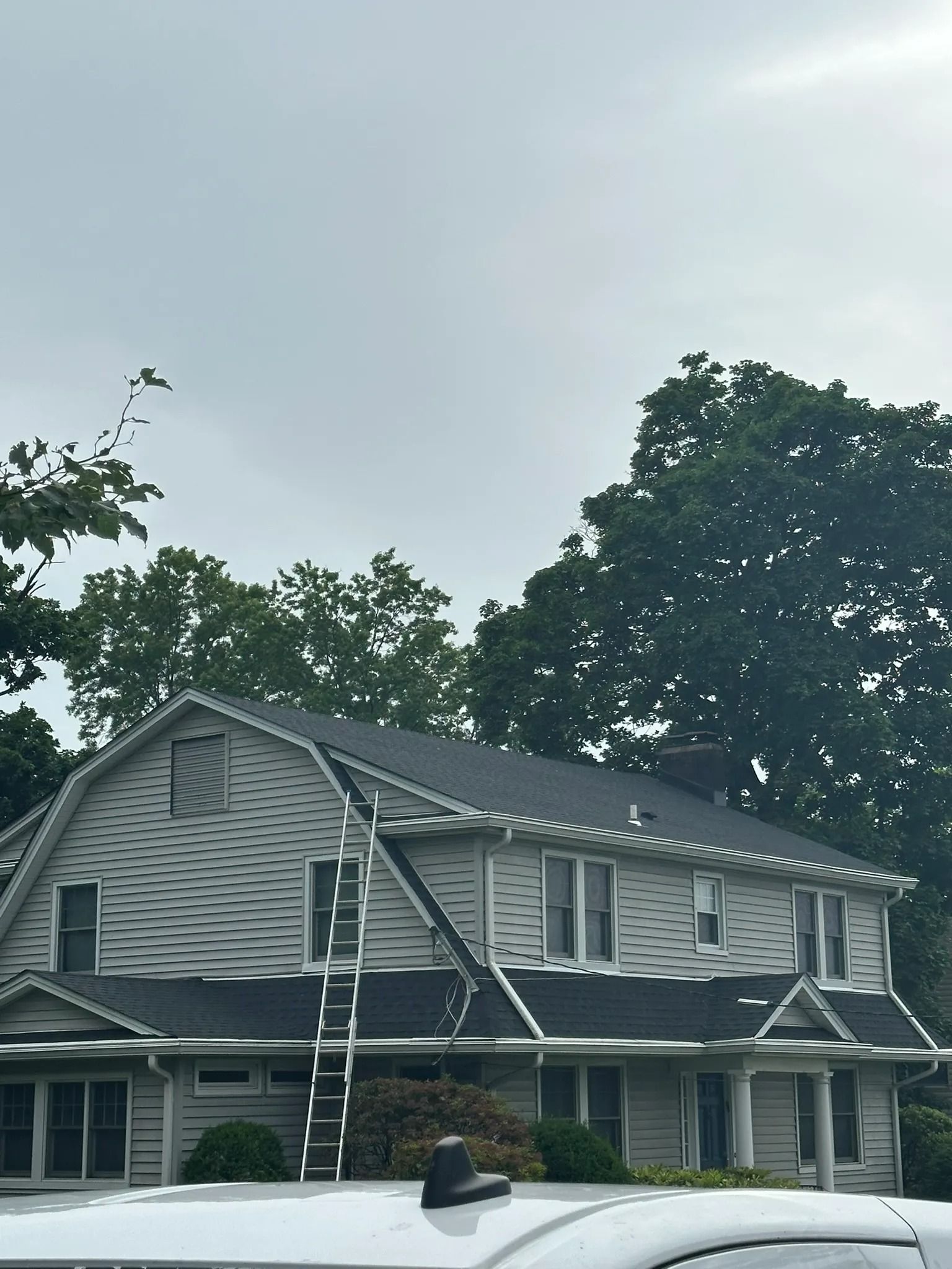 Damaged two-story house with missing roof sections and exposed framing under gray sky