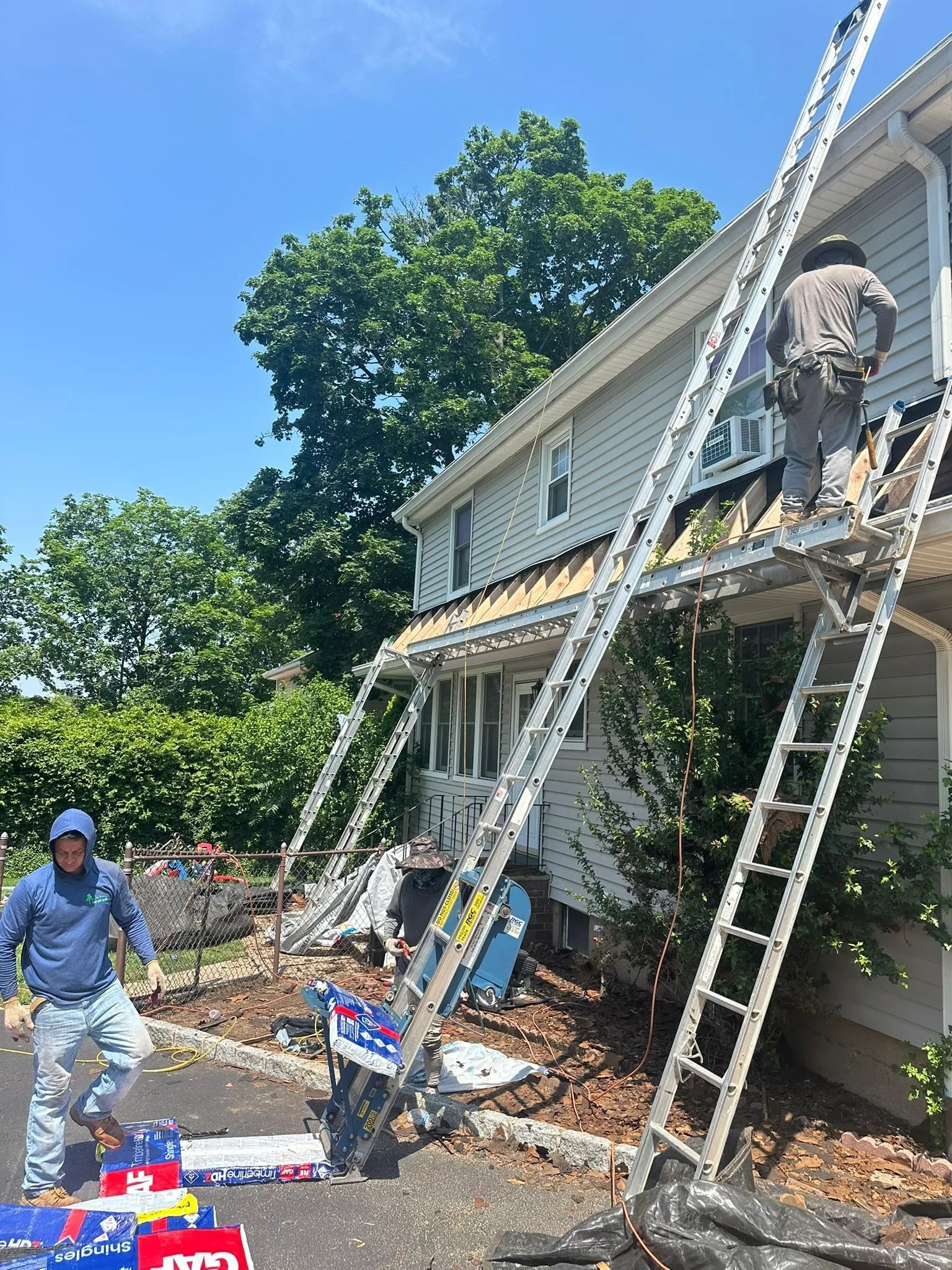 Workers on ladders repairing a house exterior with a large mural, surrounded by tools and debris.