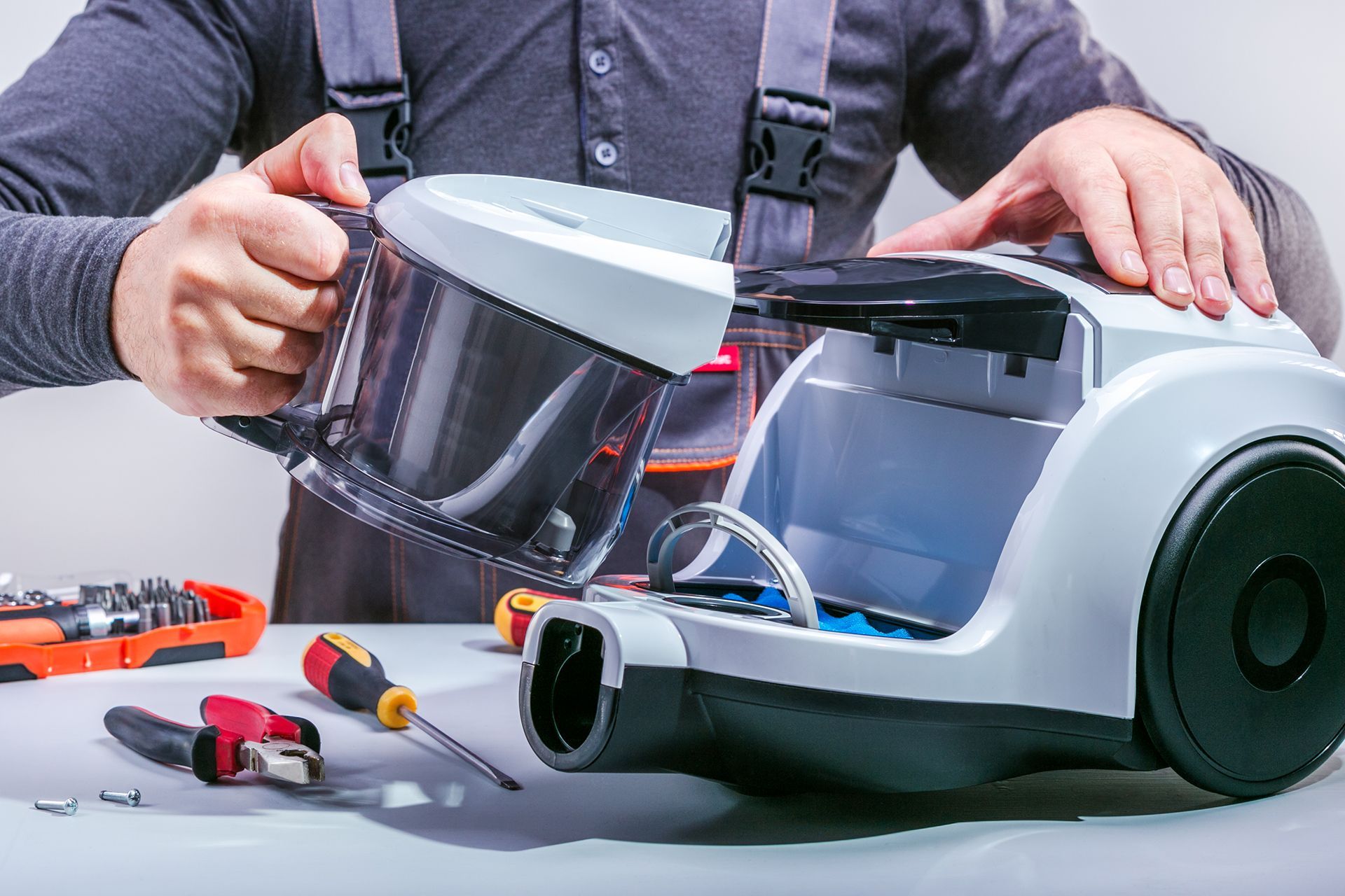 A Man Is Repairing a Vacuum Cleaner on A Table