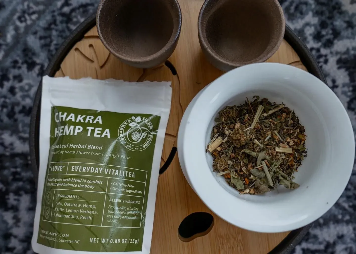 Franny's Farmacy Chakra Hemp Tea set on a wooden tray with two cups and a bowl of loose tea.