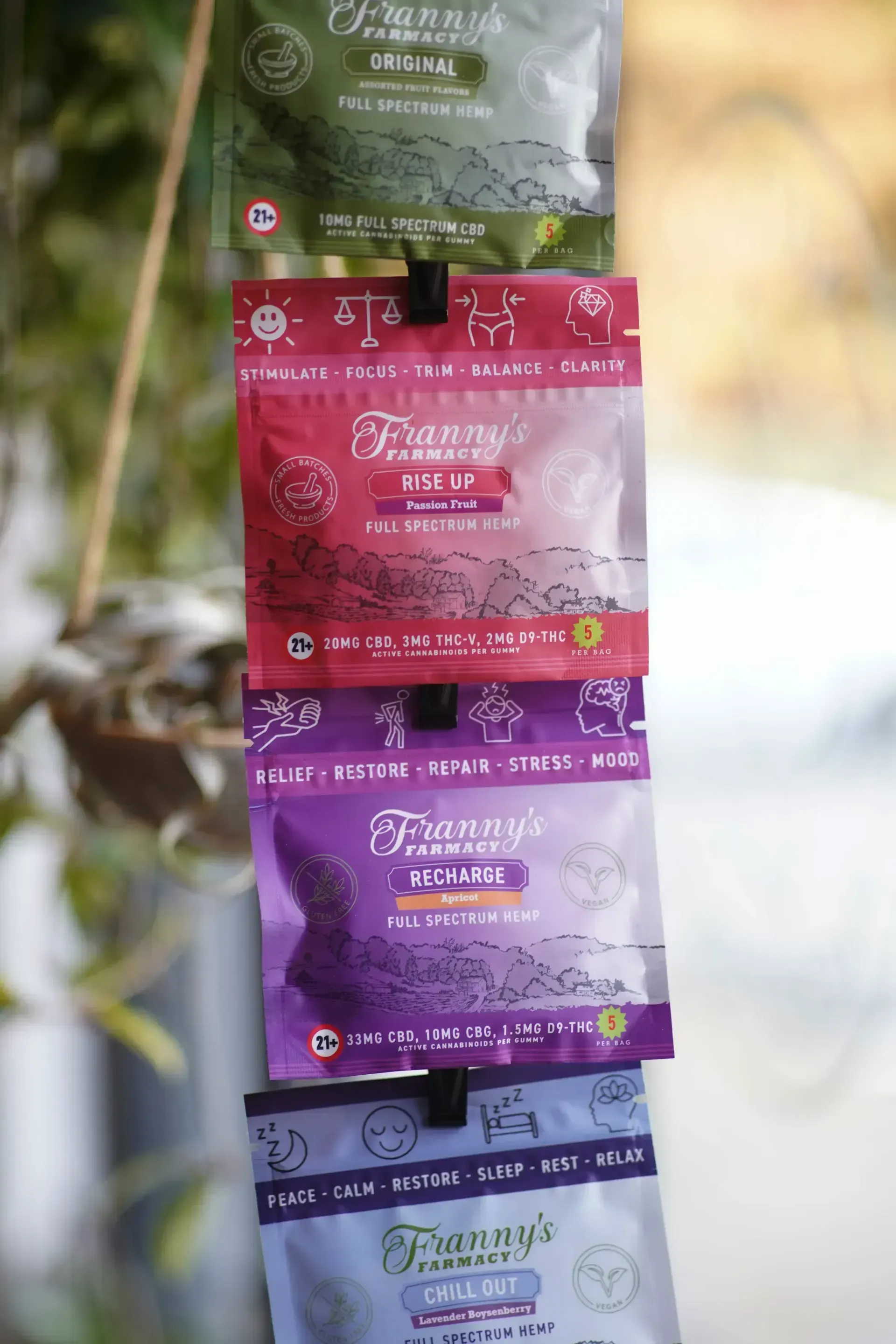 Four colorful, sealed CBD gummy pouches hanging vertically. Each bag has the brand name "Franny's Farmacy" on them