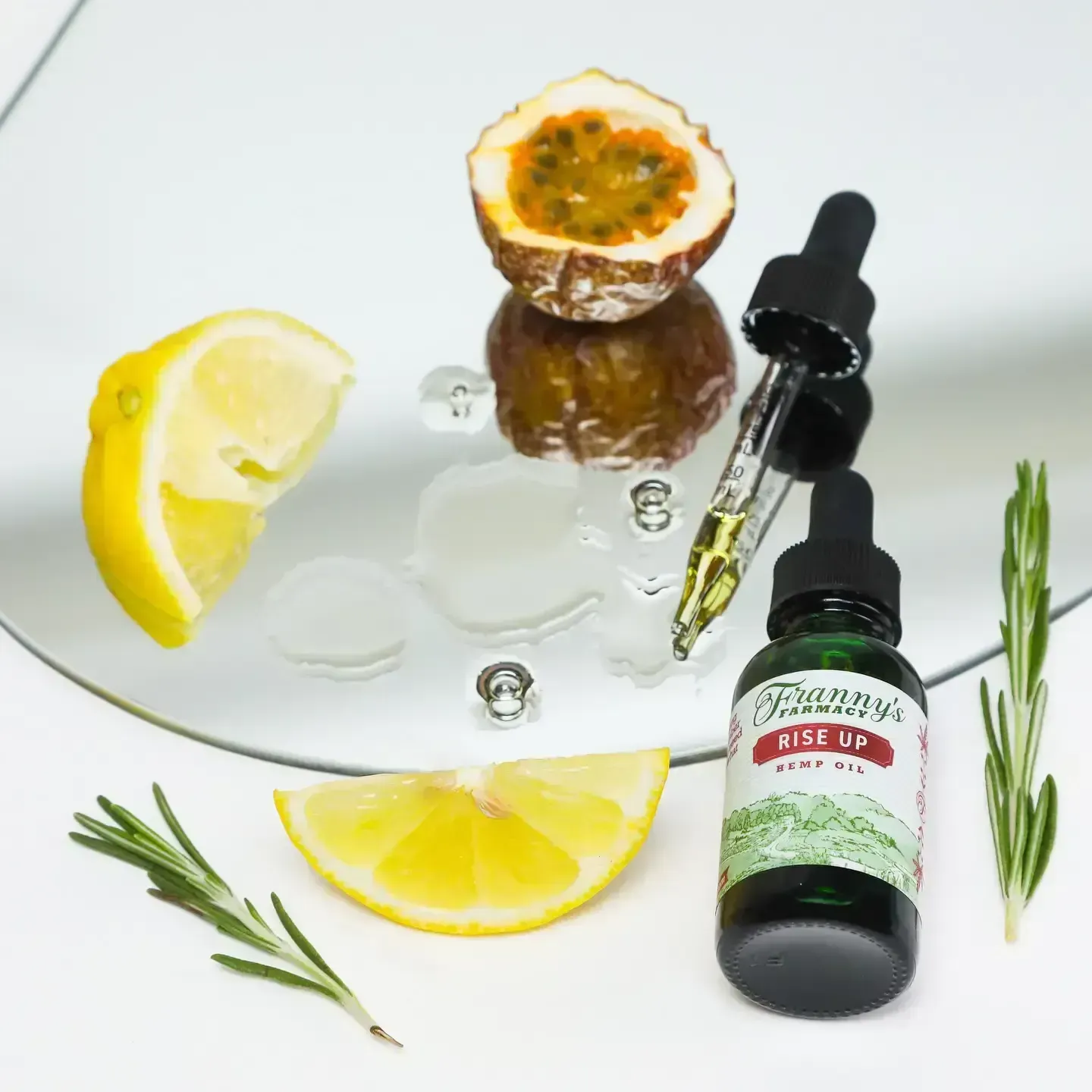 Lemon and passion fruit with cbd oil dropper bottle and rosemary sprigs on a mirror