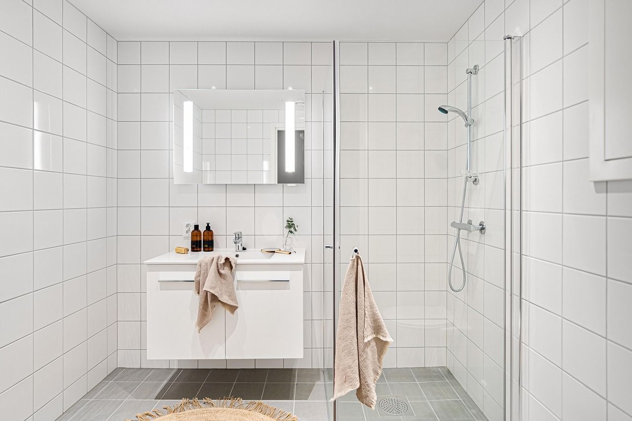 A clean modern white marbled bathroom with a standalone tub and gold trimmings